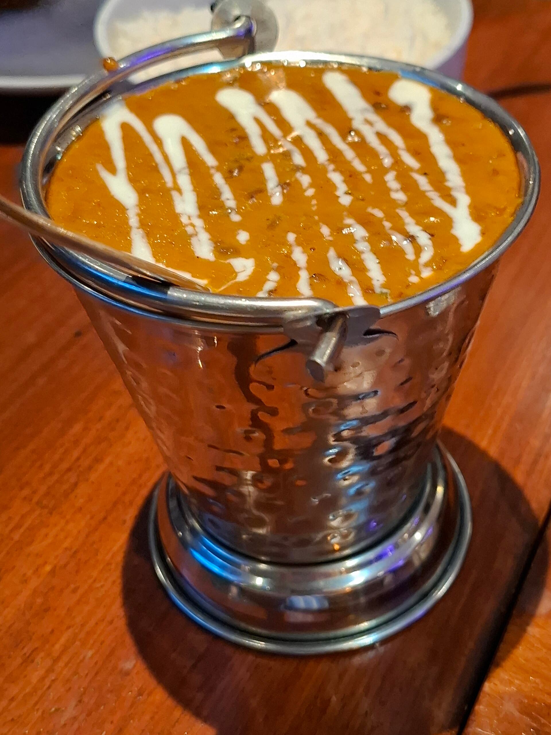 Dal makhani served in a hammered steel pot on a restaurant table