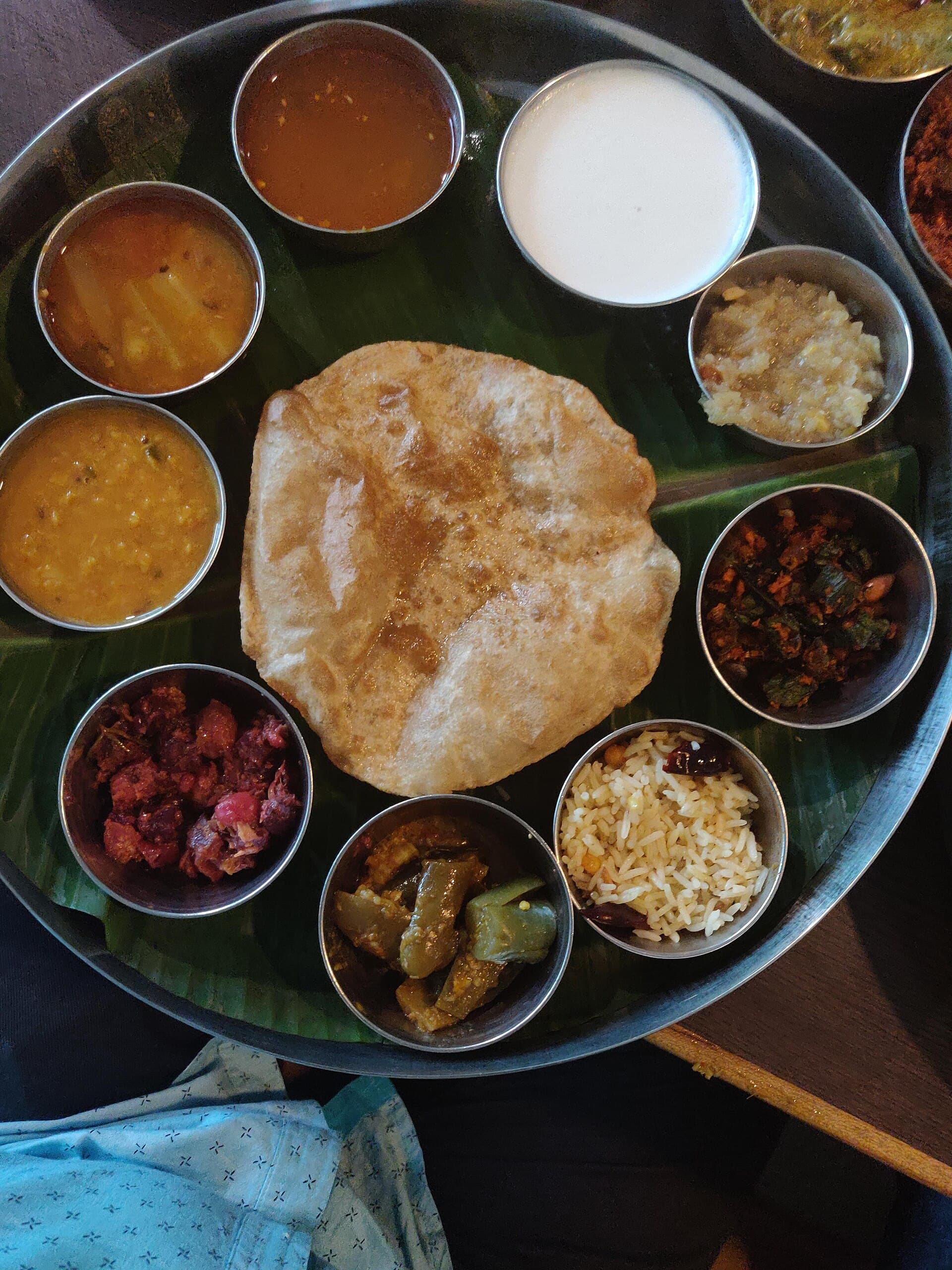 A vegetarian thali on a banana leaf with dals, puri, and sides